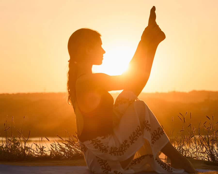 Female silhouette stretching at warm sun light