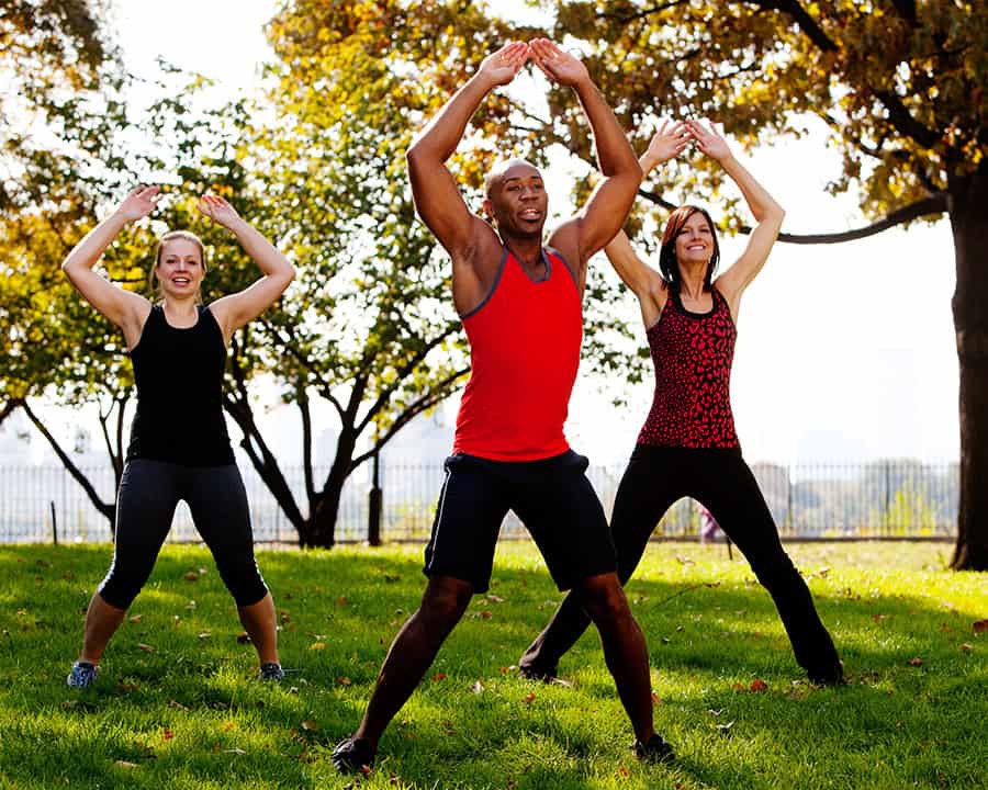 A group of people doing jumping jacks in the park