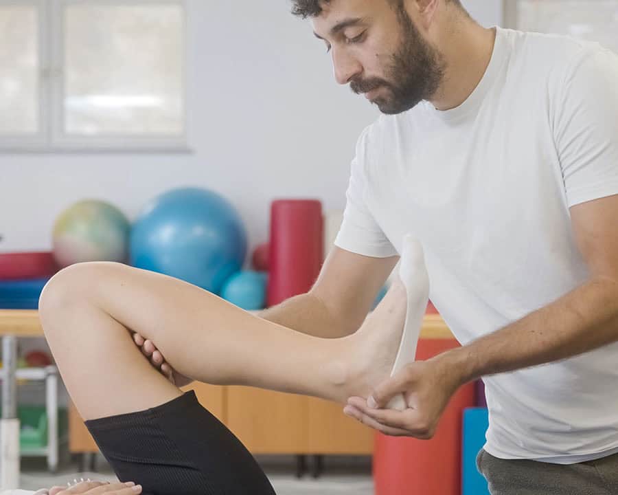 Physiotherapist doing sciatica strech exercise by bending a patient's knee