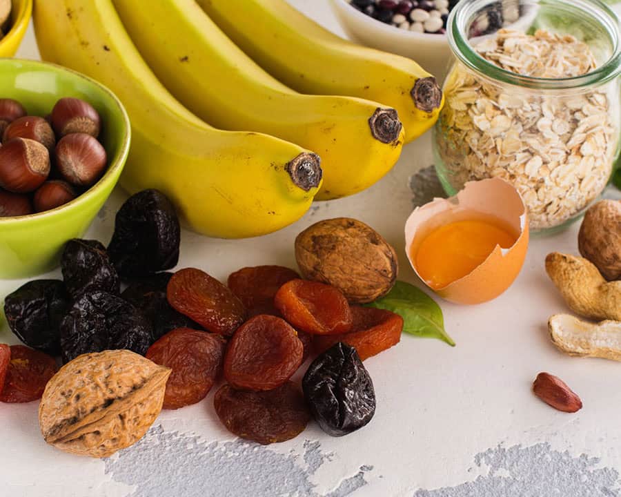 Products rich of potassium - K. Bananas, spinach, nuts, grains, dried fruits overs stone table
